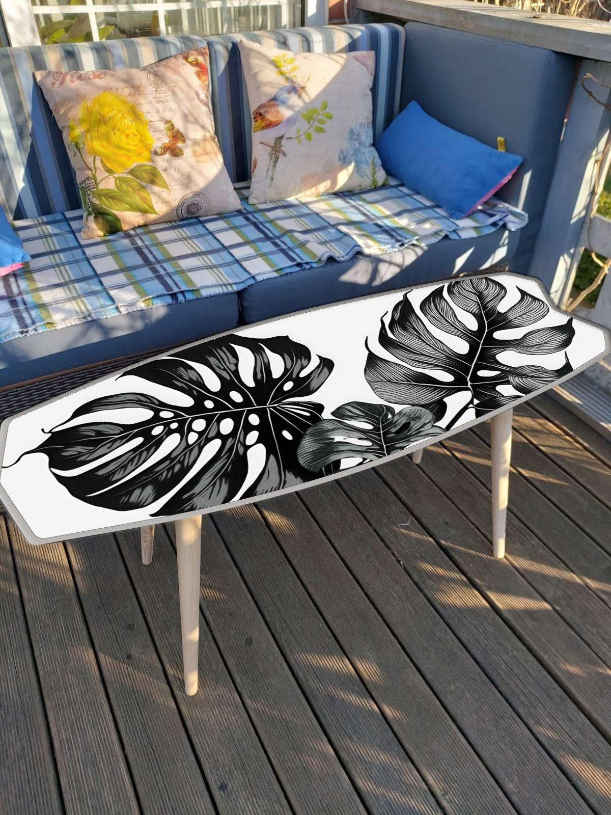 Surfboard shaped coffee table with monstery leaves in black and white design