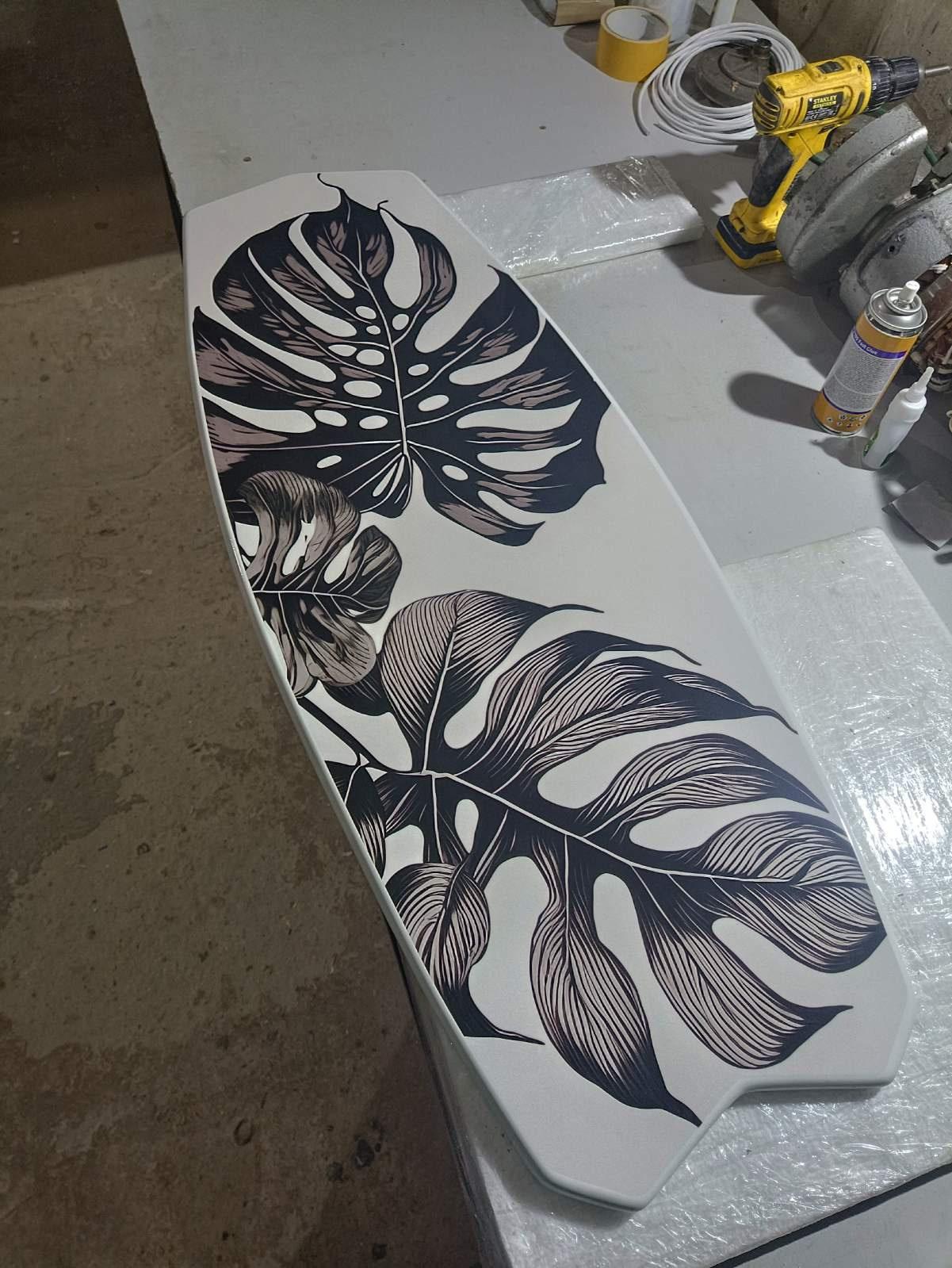 Surfboard shaped coffee table with monstery leaves in black and white design