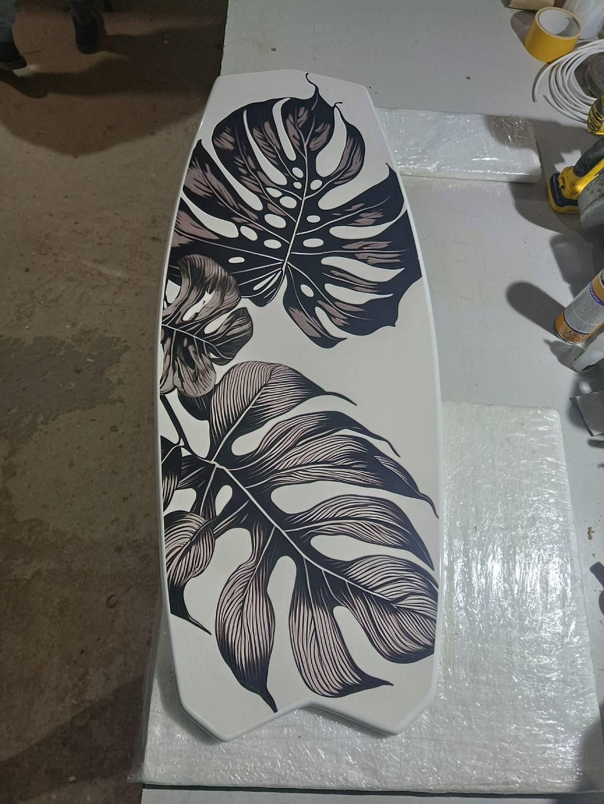Surfboard shaped coffee table with monstery leaves in black and white design
