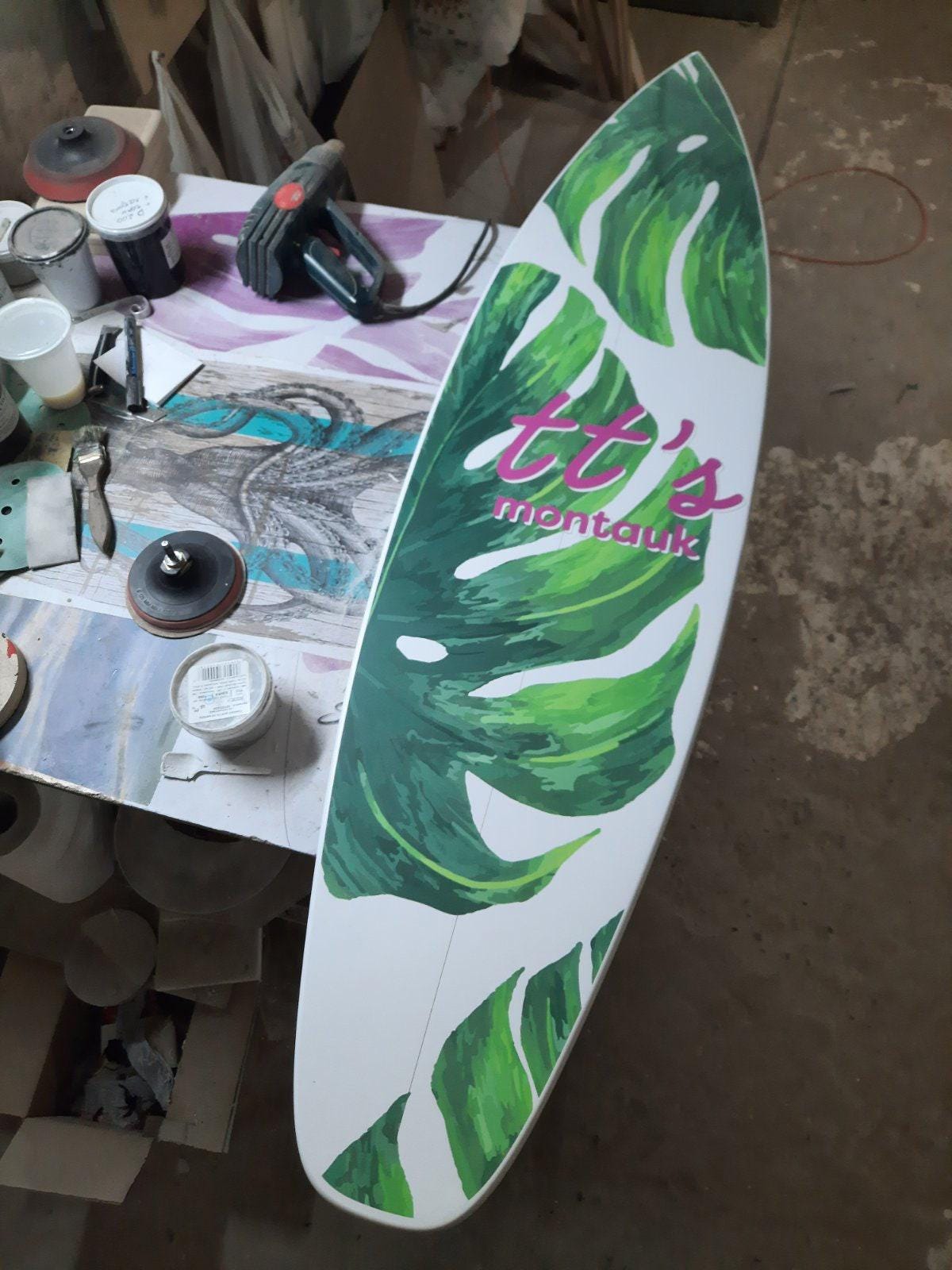 Surfboard with green monstera leaves