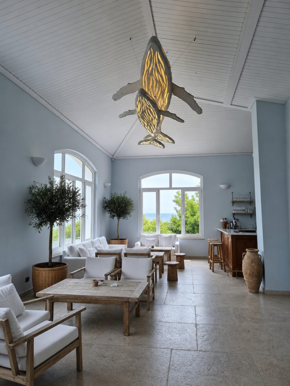 Whale and calf LED chandelier suspended in a vaulted coastal lounge